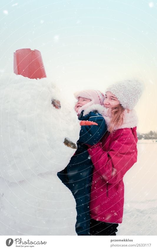 Girl and her little sister making a snowman Lifestyle Joy Happy Winter Snow Winter vacation Child Human being Young woman Youth (Young adults) Woman Adults