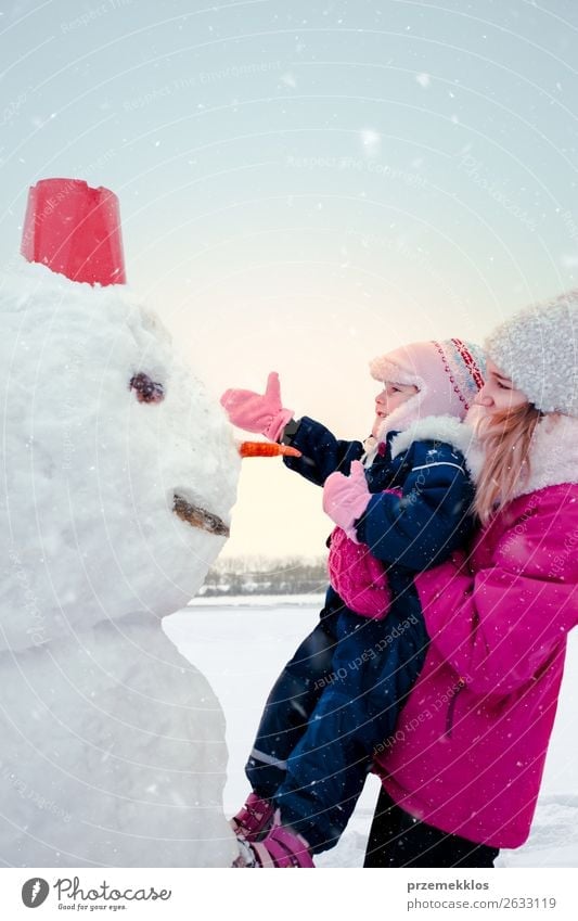 Girl and her little sister making a snowman Lifestyle Joy Happy Winter Snow Winter vacation Child Human being Young woman Youth (Young adults) Sister