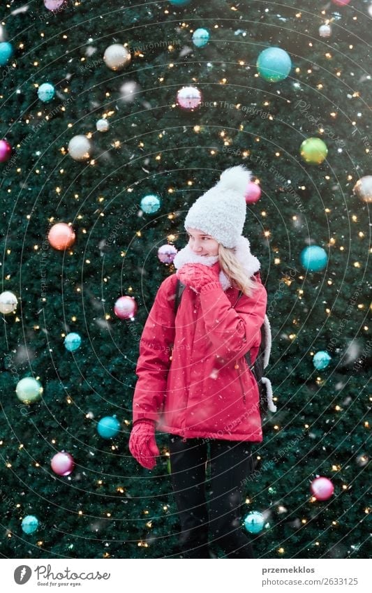 Young girl standing at front of big Christmas tree Lifestyle Joy Winter Snow Decoration Christmas & Advent Human being Young woman Youth (Young adults) Snowfall