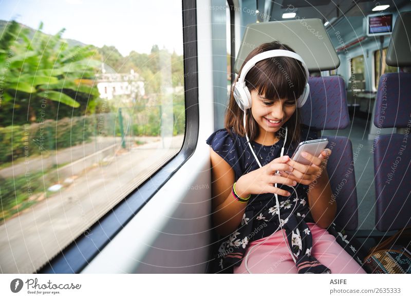 Little girl with headphones and smart phone travelling by train Joy Happy Beautiful Leisure and hobbies Vacation & Travel Trip Music Child Headset PDA