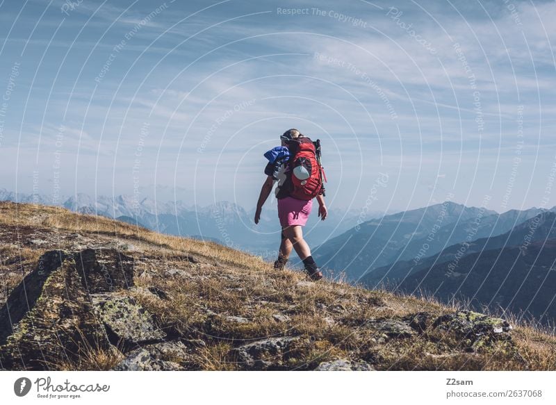 Young woman with hiking backpack stands on the edge of rain covered valley  - a Royalty Free Stock Photo from Photocase