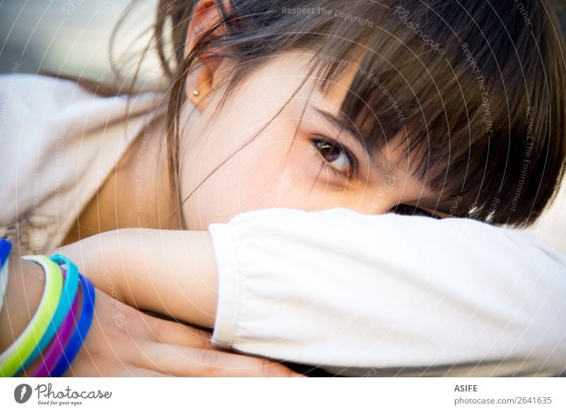 Portrait of a cute little girl with colored bracelets lying on her arm Lifestyle Face Child Woman Adults Infancy Arm Brunette Cute Emotions Colour kid shy hide