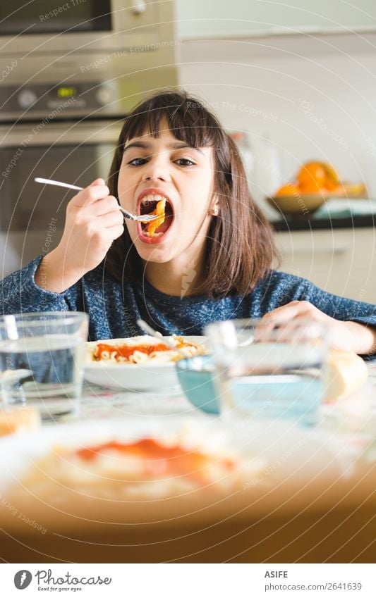 Cute and happy little girl eating pasta with tomato sauce and powdered cheese in the kitchen at home Cheese Nutrition Eating Lunch Dinner Fork Joy Happy