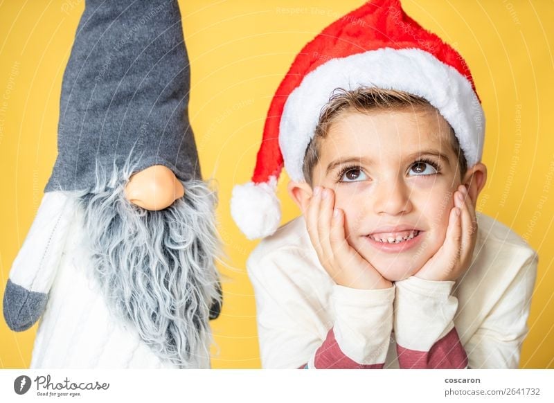 Child and a gnome with a yellow background on Christmas day Lifestyle Design Joy Happy Beautiful Face Leisure and hobbies Winter Decoration
