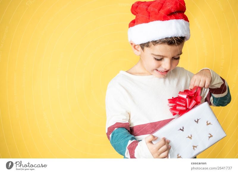 Little kid with a gift on a yellow background on Christmas Day Lifestyle Shopping Style Design Joy Happy Beautiful Winter Feasts & Celebrations