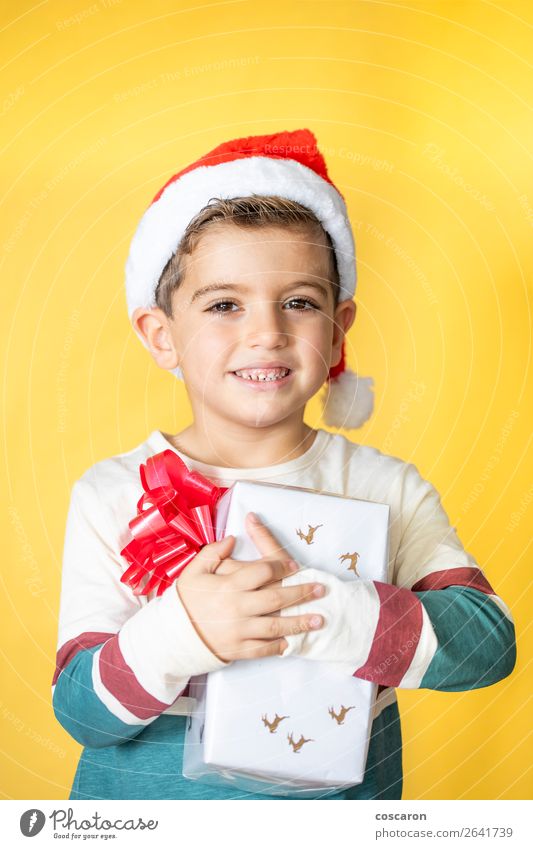 Little kid with a gift on a yellow background on Christmas Day Lifestyle Style Design Joy Happy Beautiful Winter Feasts & Celebrations Christmas & Advent Child