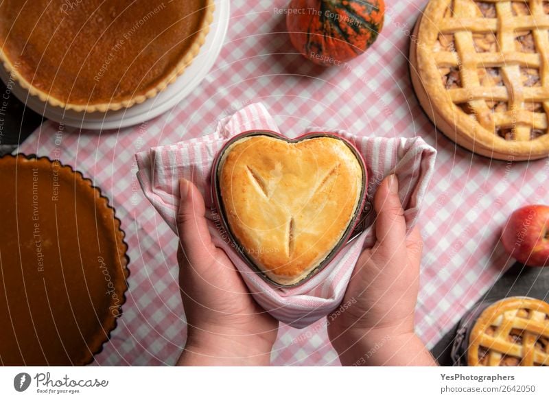 Woman hands holding a heart shaped pie above a table Dessert Kitchen Adults Autumn Exceptional Many Tradition Thanksgiving day above view American apple pies