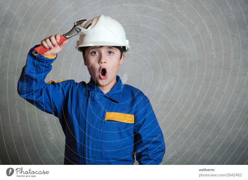 surprised child with a white helmet and holding a wrench Joy Child Work and employment Construction site Tool Hammer Human being Boy (child) Father Adults