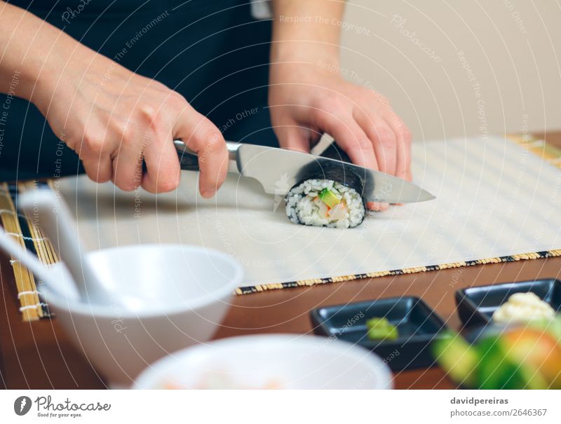 Closeup of woman chef cutting japanese sushi roll Seafood Lunch Diet Sushi Restaurant Woman Adults Hand Make Fresh maki california roll knife preparing Rice