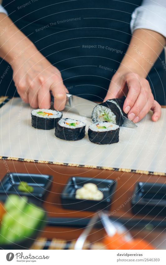 Female chef cutting japanese sushi roll Seafood Dinner Diet Sushi Restaurant Woman Adults Hand Make Fresh Tradition Cut maki roll knife Rice avocado Seaweed