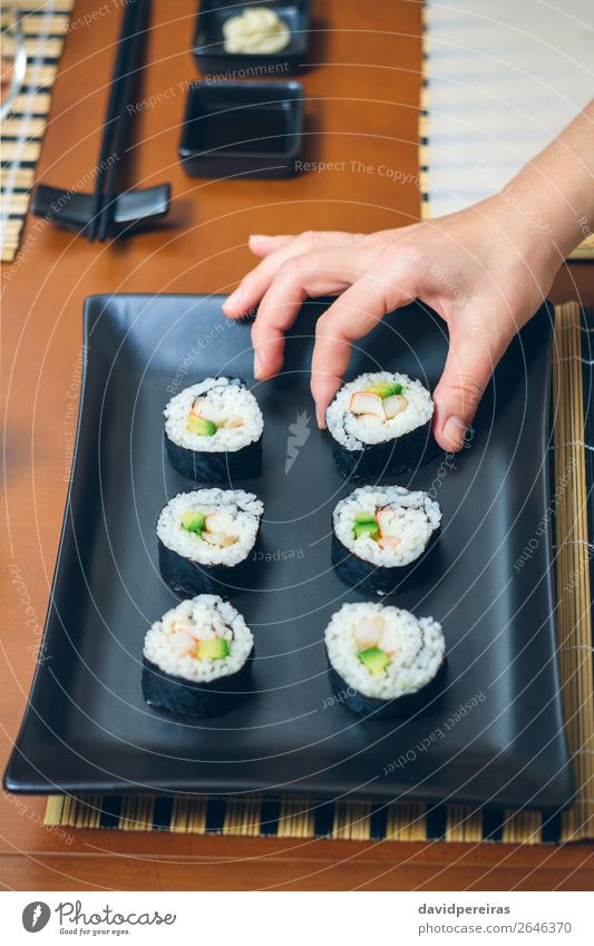 Female chef placing japanese sushi rolls on a tray Sushi Plate Restaurant Woman Adults Hand Places Make Fresh Black Take california roll Presentation Snack Tray