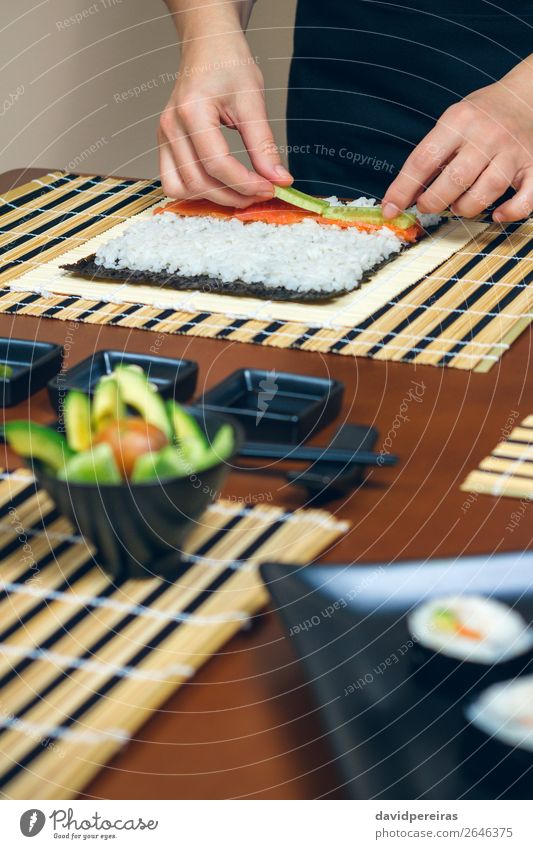 Chef hands placing ingredients on rice Seafood Diet Sushi Bowl Restaurant Human being Woman Adults Hand Make Fresh chef careful cucumber Salmon Rice maki roll