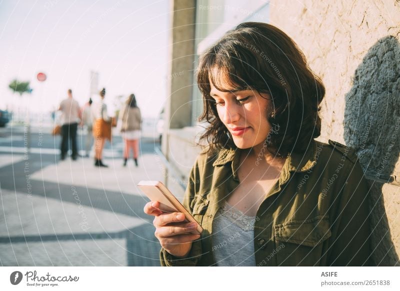Young woman using her smart phone in the street at sunset Happy Beautiful Leisure and hobbies Telephone Cellphone PDA Technology Woman Adults Autumn Street