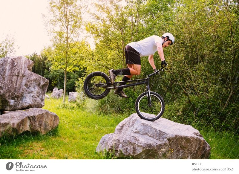 Young trial cyclist making tricks in a rock circuit Freedom Summer Mountain Sports Cycling Man Adults Nature Tree Forest Rock Jump Strong Rider bike Extreme