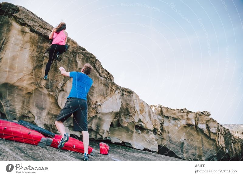 Young couple rock climbing cliffs at the coast helping eachother Joy Leisure and hobbies Adventure Ocean Mountain Hiking Sports Climbing Mountaineering Woman