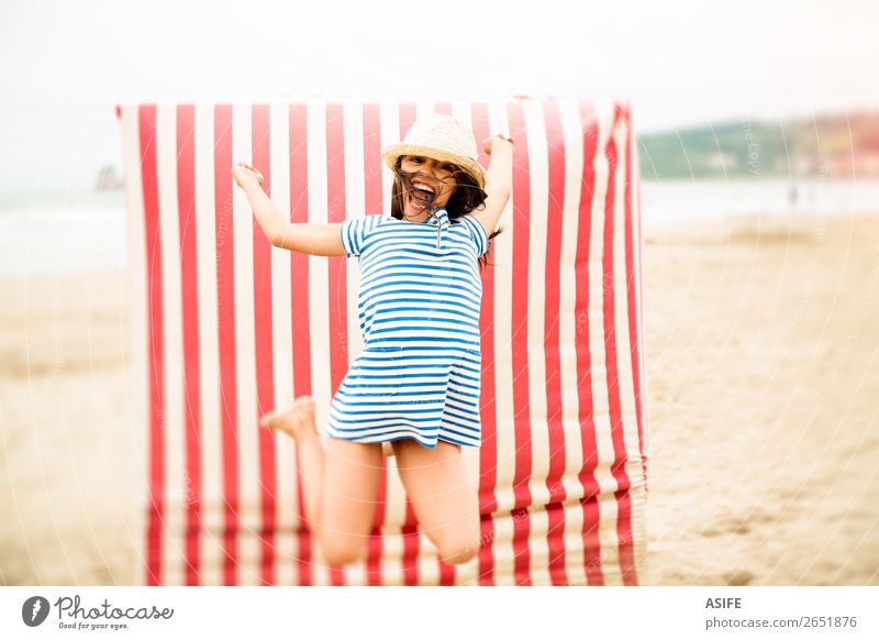 Crazy for vacation Joy Happy Beautiful Playing Vacation & Travel Summer Beach Child Dress Hat Brunette Smiling Laughter Jump Funny Cute Blue Red kid girl