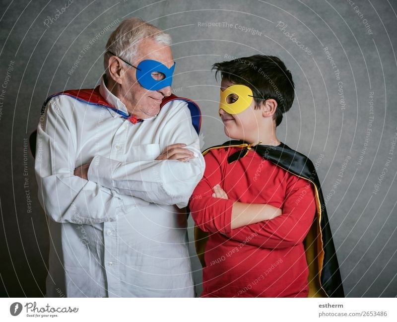 Grandfather With Grandson dressed as a superhero on gray background Lifestyle Joy Adventure Feasts & Celebrations Carnival Fairs & Carnivals Retirement