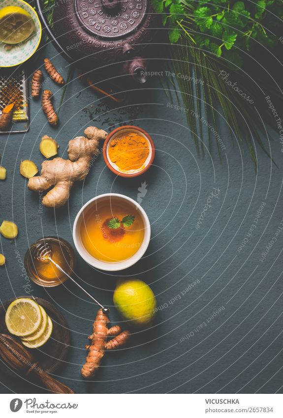 Healthy turmeric spice tea preparation on gray background with teapot, cup of tea,  lemon,  ginger, cinnamon sticks and honey , top view.  Immune boosting remedy , detox and dieting concept