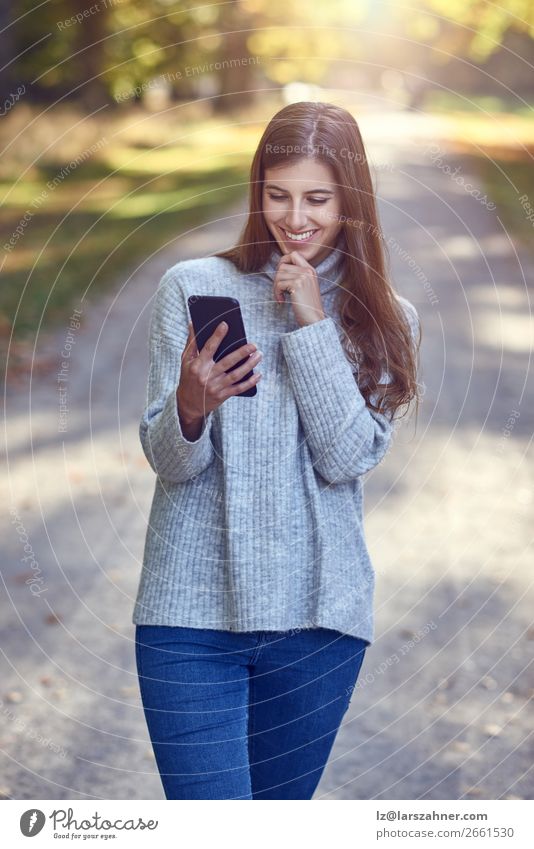 Woman using smartphone in park Lifestyle Happy Beautiful Reading Summer Telephone PDA Technology Internet Adults 1 Human being 18 - 30 years