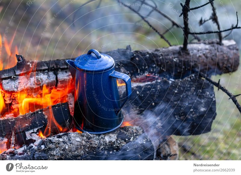 Campfire with coffee pot and kettle at a river in the wilderness