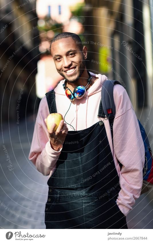 Young black man eating an apple walking down the street. Fruit Apple Eating Lifestyle Happy Beautiful Human being Masculine Young man Youth (Young adults) Man