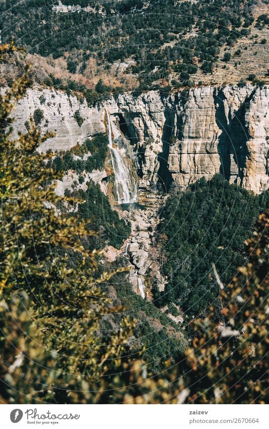 A detail of a cliff with a waterfall framed by the leaves of some trees Beautiful Calm Vacation & Travel Adventure Mountain Hiking Environment Nature Landscape