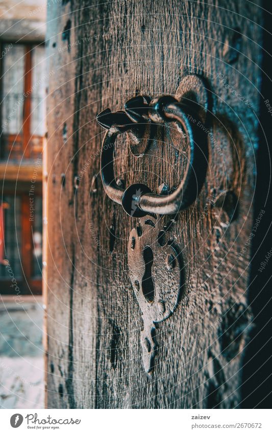 A lock and a handle of a medieval wooden door captured from the side with the village's street in the background Design Vacation & Travel Tourism