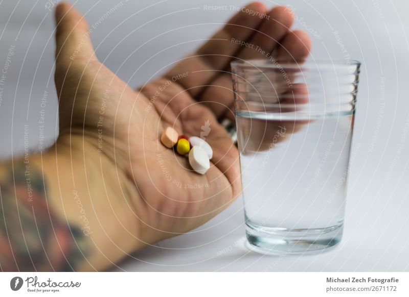men showing pills in different colors beside a glass of water Bowl Medical treatment Illness Medication Science & Research Hand Wood Blue Yellow Pink White