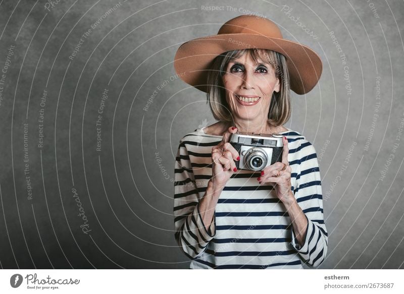 Portrait of Smiling senior woman with vintage photo camera on gray background Lifestyle Joy Leisure and hobbies Vacation & Travel Tourism Trip Adventure
