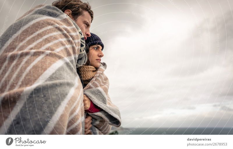Young couple under blanket looking the sea in a cold day Lifestyle Happy Beautiful Ocean Winter Mountain Woman Adults Man Couple Nature Sky Clouds Autumn Wind
