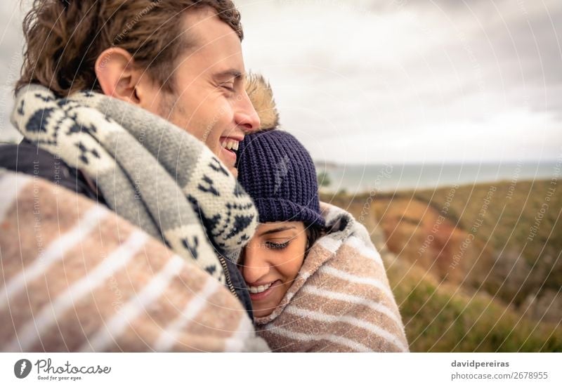 Young couple laughing outdoors under blanket in a cold day Lifestyle Happy Beautiful Ocean Winter Mountain Woman Adults Man Couple Nature Sky Clouds Autumn Wind