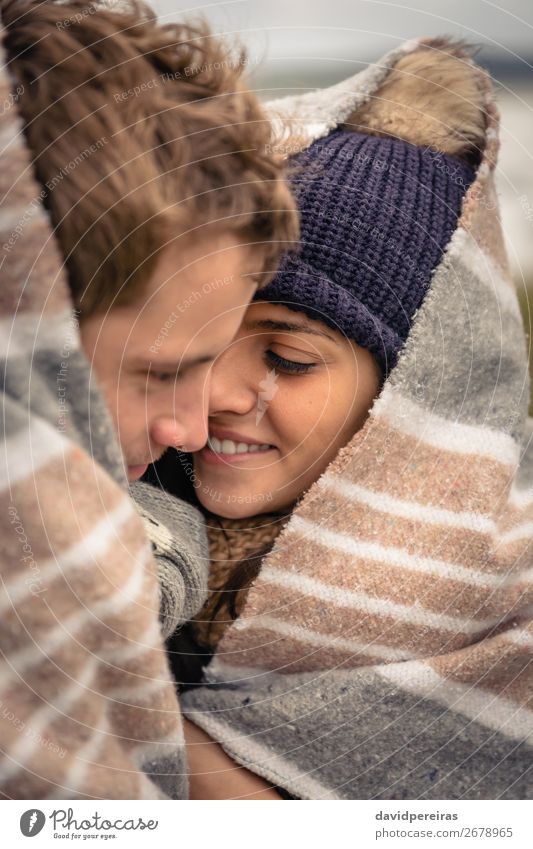 Young couple embracing outdoors under blanket in a cold day Lifestyle Happy Beautiful Winter Woman Adults Man Couple Nature Sky Clouds Autumn Wind Scarf Hat