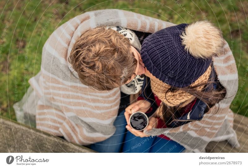 Young couple under blanket with hot drink kissing outdoors Beverage Coffee Tea Lifestyle Adventure Winter Table Woman Adults Man Couple Hand Nature Autumn