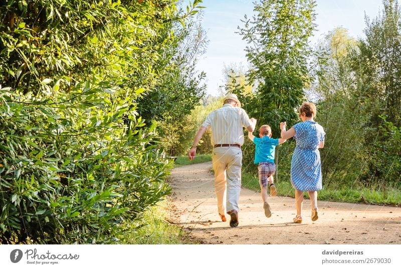 Grandparents and grandchild jumping on nature path Lifestyle Joy Happy Leisure and hobbies Child Boy (child) Woman Adults Man Parents Grandfather Grandmother