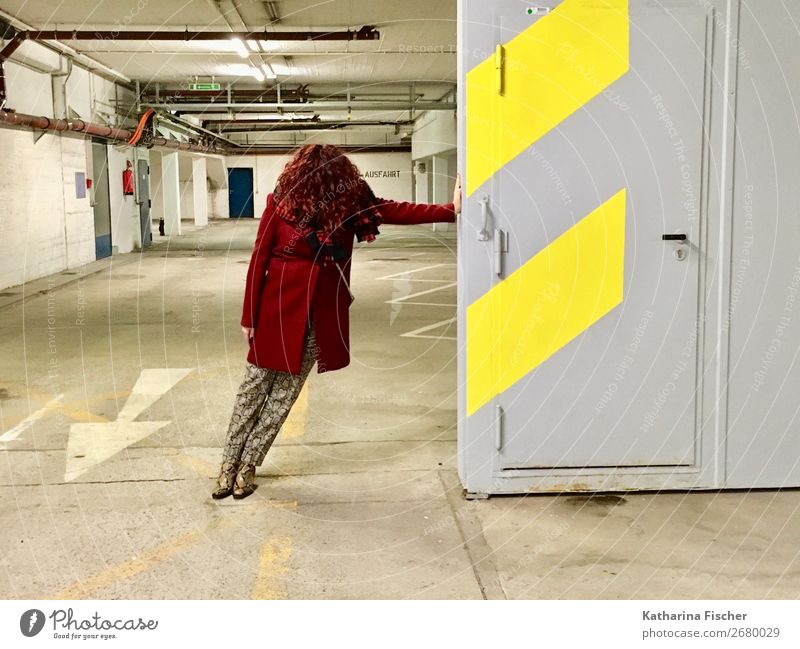 Red-haired woman is standing in an underground car park. Feminine 1 Human being Pants Coat Scarf Footwear Curl Line Stand Brown Yellow Gray White