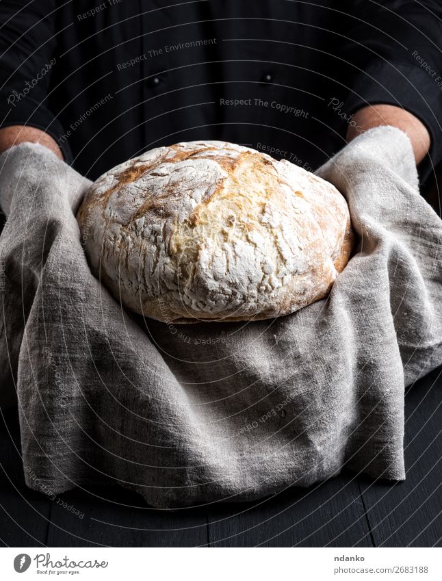 baked round homemade bread on a gray napkin Bread Nutrition Table Kitchen Cook Human being Hand Wood Eating Make Dark Fresh Brown Black White Tradition Baking