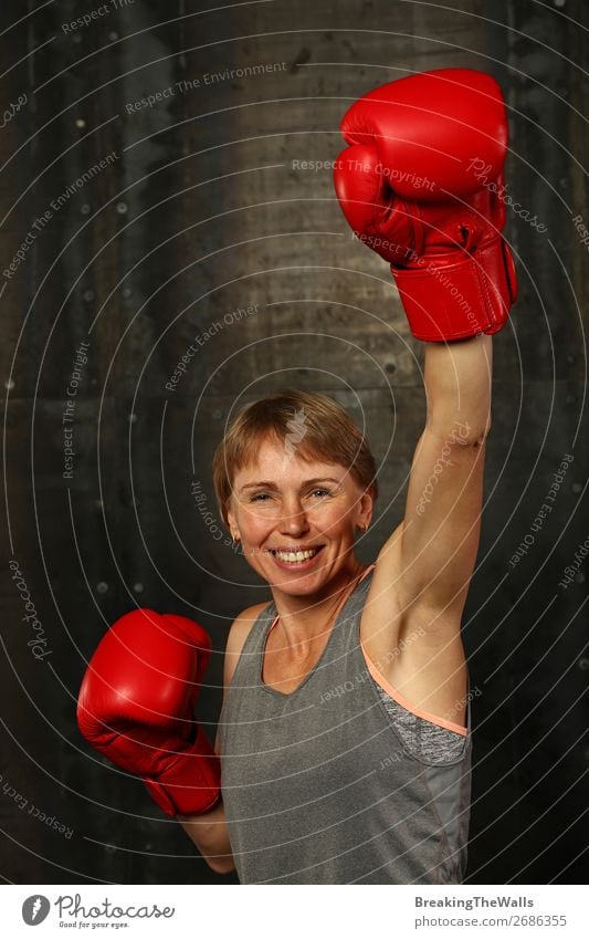 Front portrait of young adult woman in red boxing gloves with hand up gesture of winner or champion, smiling and looking at camera Joy Sports Fitness