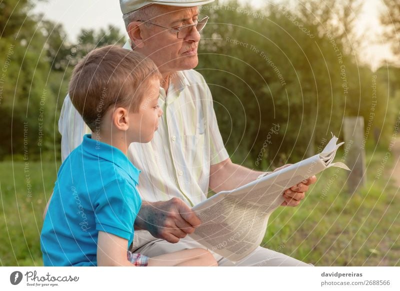 Senior man and child reading a newspaper outdoors Lifestyle Happy Relaxation Leisure and hobbies Reading Child School Human being Boy (child) Man Adults Parents