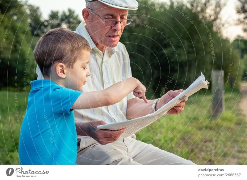 Senior man and child reading a newspaper outdoors Lifestyle Happy Leisure and hobbies Reading Child School Human being Boy (child) Man Adults Parents