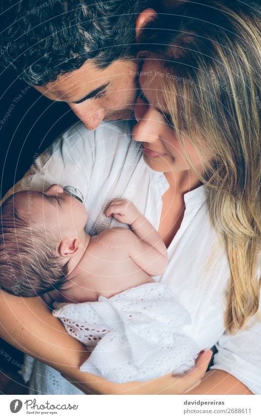 Couple embracing a newborn over dark background - a Royalty Free