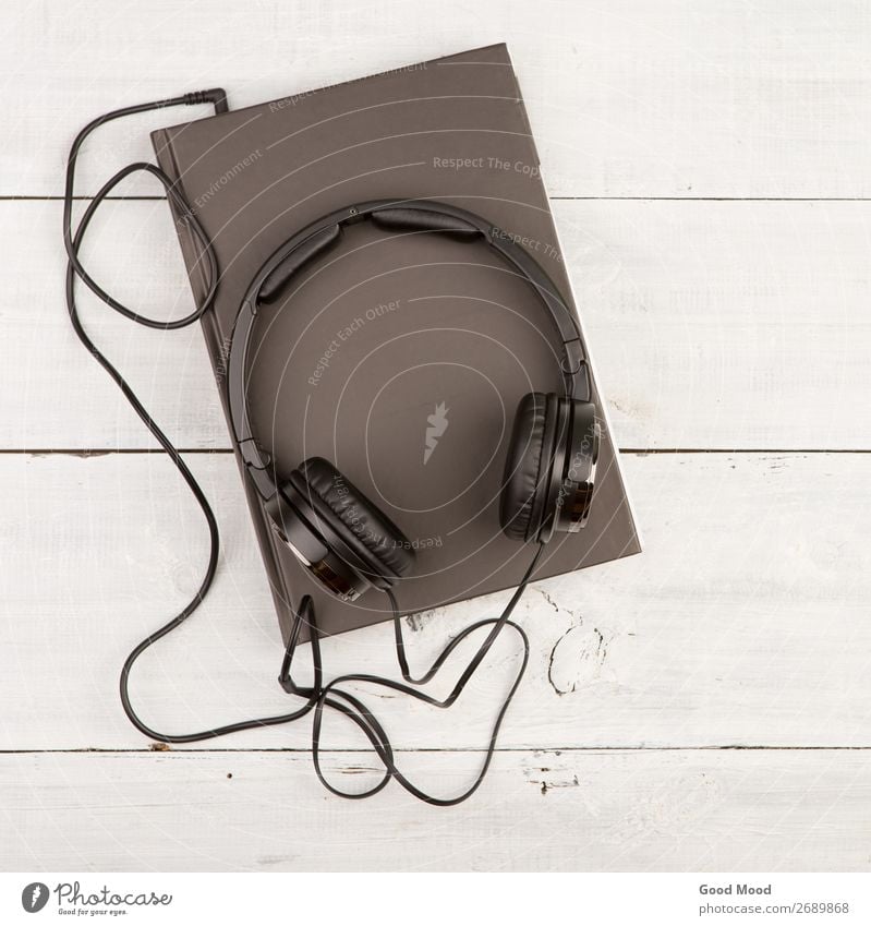 Audio book concept with black book and headphones Leisure and hobbies Playing Reading Music School Study Headset Technology Media Book Library Paper Wood