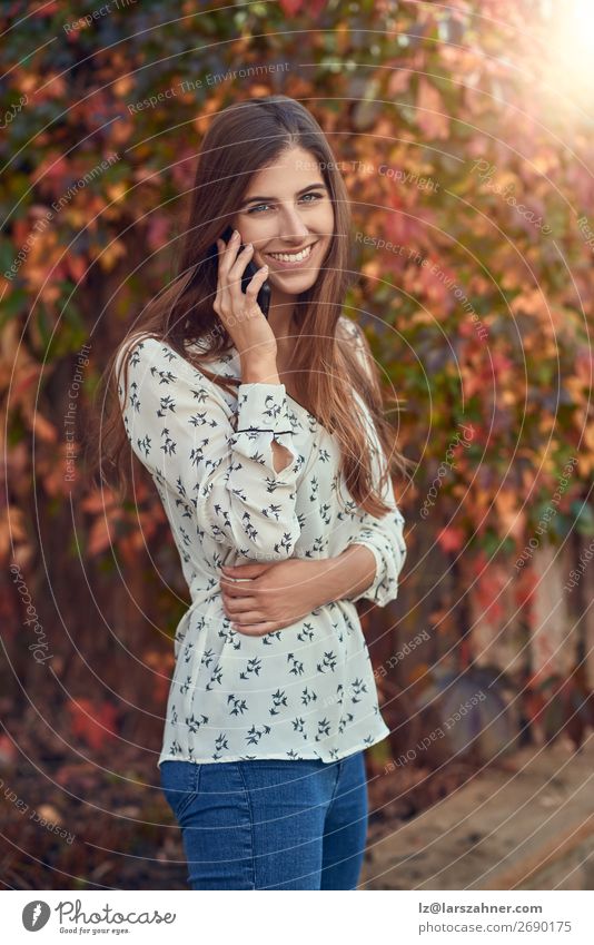 Smiling young woman chatting on a mobile in autumn Happy Face Summer Business Telephone PDA Woman Adults 1 Human being 18 - 30 years Youth (Young adults) Autumn