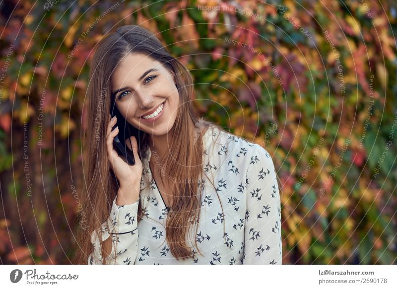 Smiling young woman chatting on a mobile in autumn Happy Face Summer Business Telephone PDA Woman Adults 1 Human being 18 - 30 years Youth (Young adults) Autumn