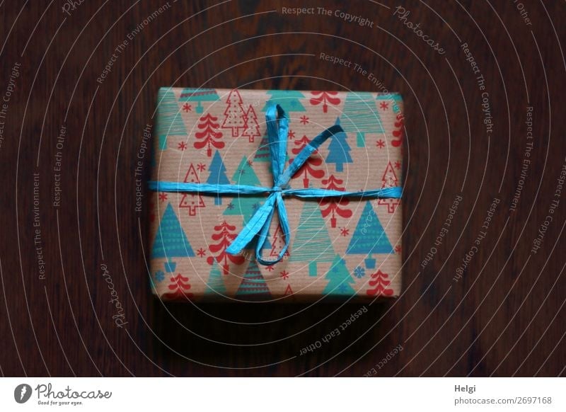 small parcel as a gift wrapped in red-blue-turquoise paper with Christmas motives and turquoise bast bow Piece of paper Packaging Decoration Bow Gift
