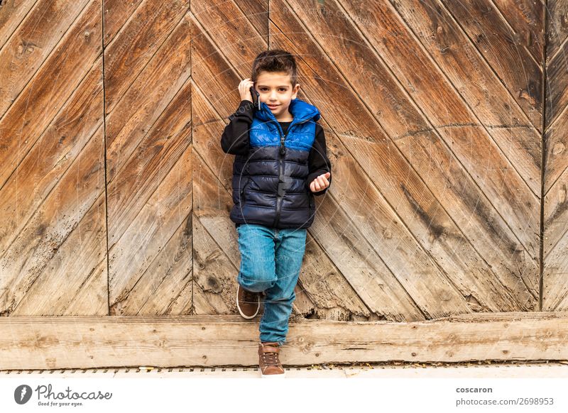 Little boy with a mibile phone with a wooden door background Lifestyle Style Design Beautiful Playing Vacation & Travel Winter House (Residential Structure)