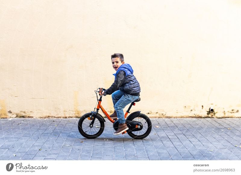 Little kid riding his bicycle on city street Lifestyle Joy Happy Relaxation Leisure and hobbies Playing Children's game Summer Sun Sports Success Cycling