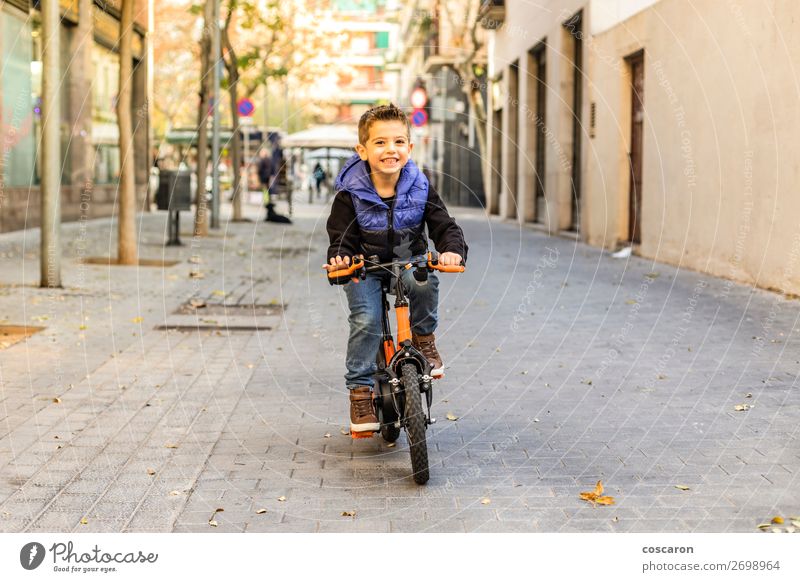 Little kid riding his bicycle on city street Lifestyle Joy Happy Beautiful Face Relaxation Leisure and hobbies Playing Sun Winter Sports Success Cycling Bicycle