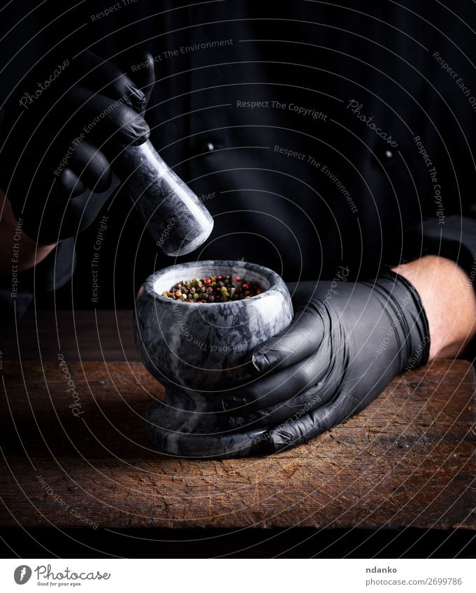 Chef in black latex gloves holds a stone mortar Herbs and spices Table Kitchen Work and employment Cook Tool Human being Man Adults Hand Gloves Stone Wood Dark