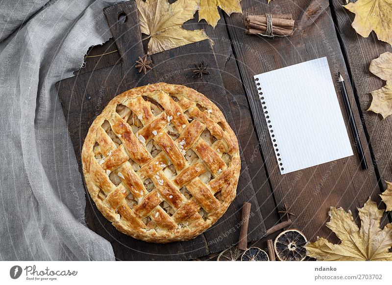 round apple pie on a brown wooden board Fruit Cake Dessert Candy Dinner Table Kitchen Autumn Leaf Paper Pen Wood Above Brown Yellow White Tradition American