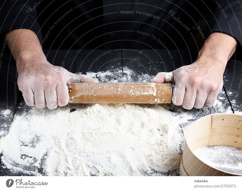 wooden rolling pin in men's hands Dough Baked goods Bread Table Kitchen Work and employment Cook Human being Hand Wood Make Fresh Black White background Baking